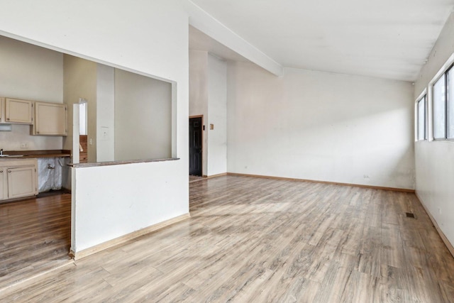 unfurnished living room with sink, high vaulted ceiling, and light wood-type flooring