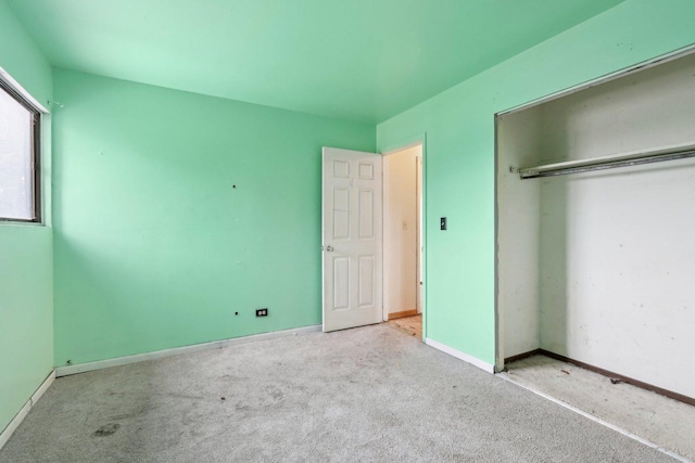 unfurnished bedroom featuring light carpet and a closet