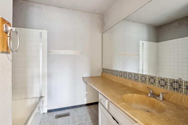 bathroom with vanity, tiled shower / bath combo, and wood-type flooring