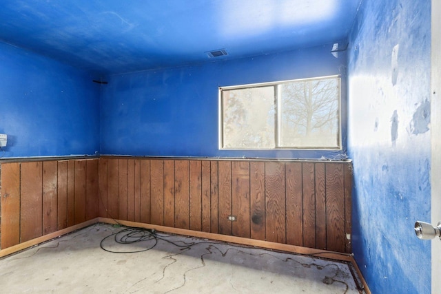 empty room with wooden walls and concrete flooring