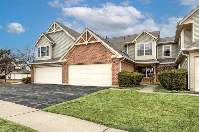 view of front of home with driveway, brick siding, a front lawn, and roof with shingles