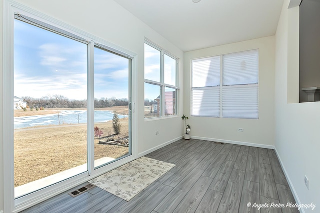 unfurnished sunroom featuring a water view