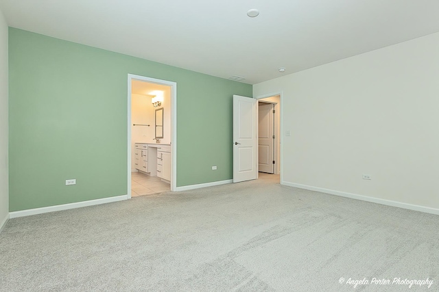 unfurnished bedroom featuring light carpet and ensuite bath