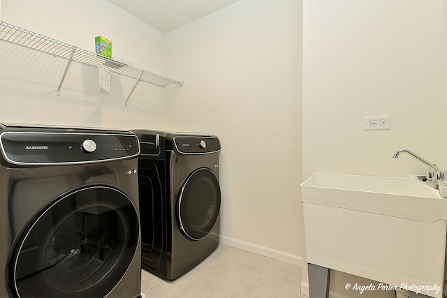 laundry area featuring sink, light tile patterned floors, and washer and clothes dryer