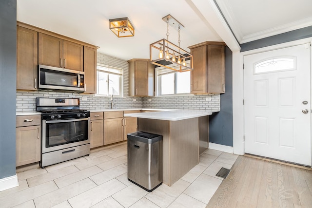 kitchen featuring appliances with stainless steel finishes, decorative light fixtures, tasteful backsplash, sink, and crown molding