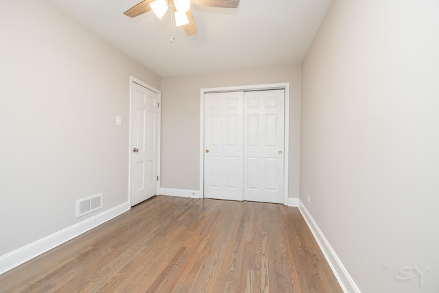 unfurnished bedroom featuring ceiling fan, light hardwood / wood-style floors, and a closet