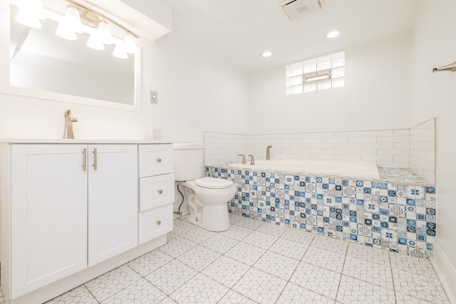 bathroom with vanity, tiled tub, and toilet