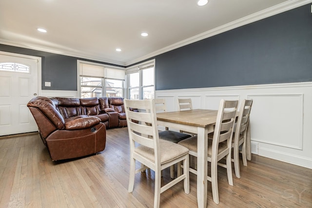 dining area with crown molding and light hardwood / wood-style flooring