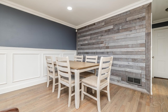 dining space featuring a fireplace, crown molding, and light hardwood / wood-style flooring