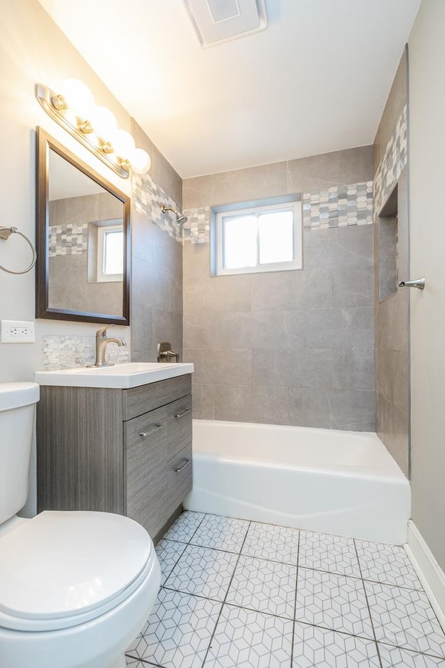 full bathroom featuring tile patterned floors, vanity, toilet, and tiled shower / bath combo