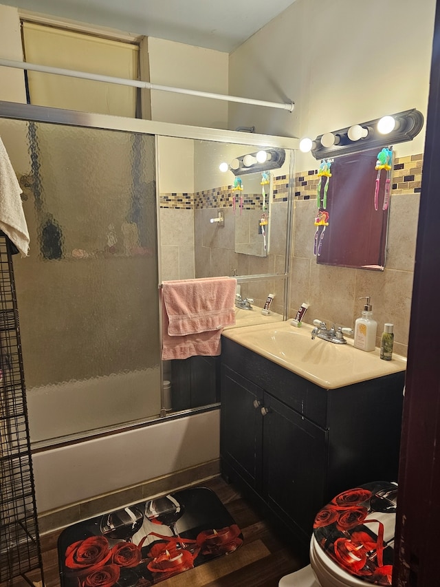 full bathroom featuring tile walls, backsplash, enclosed tub / shower combo, vanity, and toilet