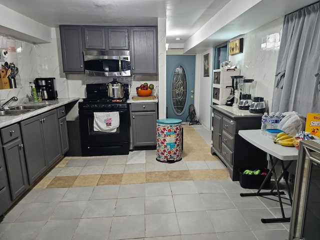 kitchen with black range with gas cooktop, sink, decorative backsplash, and gray cabinets