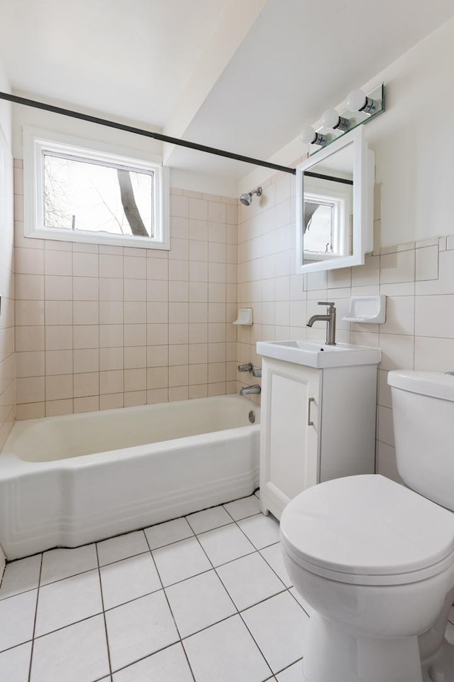 full bathroom with tile walls, tiled shower / bath combo, vanity, toilet, and tile patterned floors