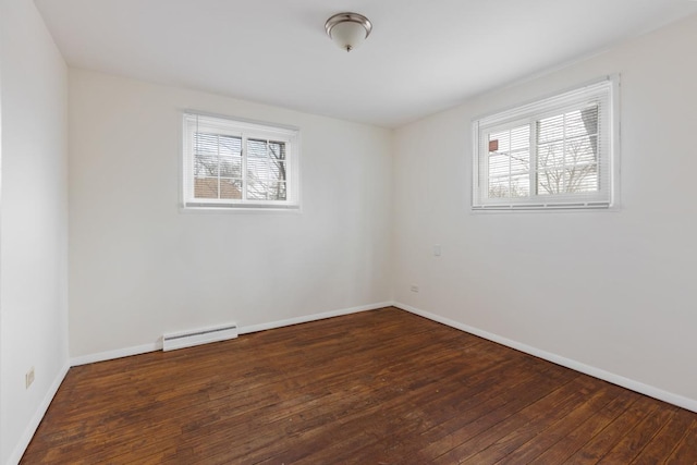 empty room featuring plenty of natural light, dark hardwood / wood-style flooring, and a baseboard heating unit