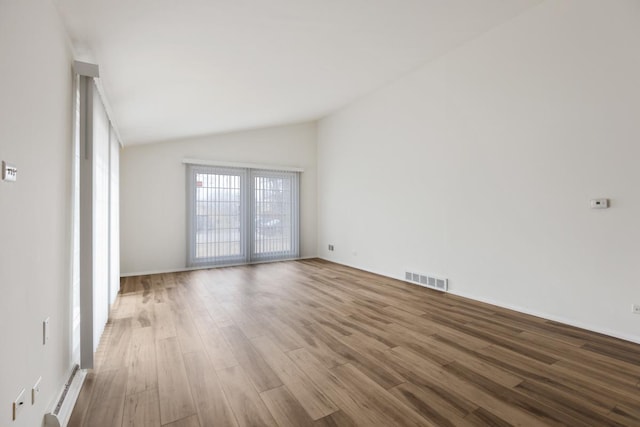 spare room with lofted ceiling and hardwood / wood-style floors