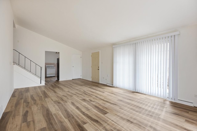 unfurnished living room with lofted ceiling, light hardwood / wood-style floors, and baseboard heating