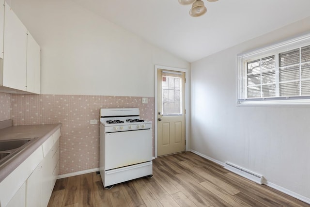 kitchen with gas range gas stove, white cabinetry, vaulted ceiling, light hardwood / wood-style flooring, and a baseboard radiator