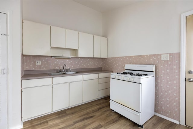 kitchen with sink, white cabinetry, wood-type flooring, tile walls, and white range with gas cooktop