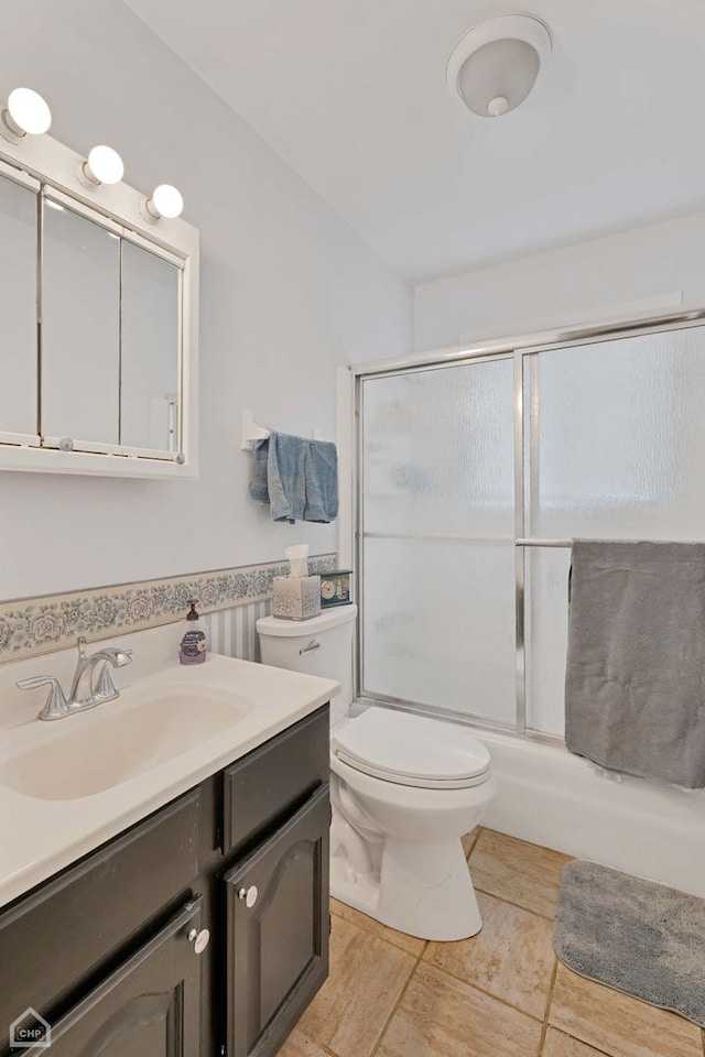 full bathroom featuring toilet, vanity, and shower / bath combination with glass door