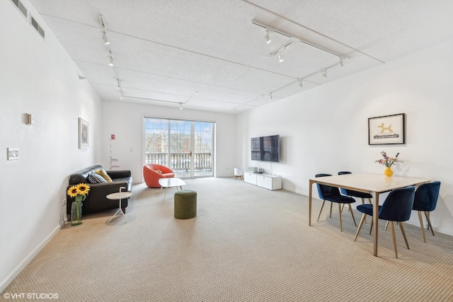 living area featuring carpet, a textured ceiling, visible vents, and track lighting