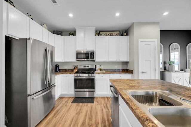 kitchen featuring white cabinetry, sink, light hardwood / wood-style flooring, and appliances with stainless steel finishes