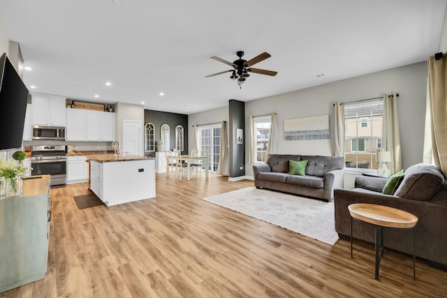 living room with ceiling fan, sink, and light wood-type flooring