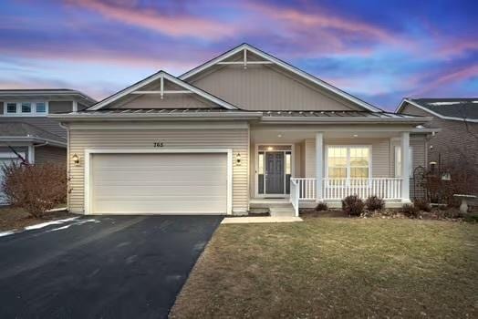 view of front of property featuring a garage, a lawn, and covered porch