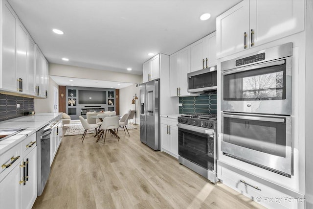 kitchen with white cabinetry, backsplash, stainless steel appliances, light stone countertops, and light hardwood / wood-style flooring