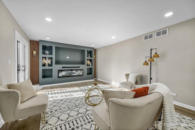 living room with built in features and light hardwood / wood-style floors