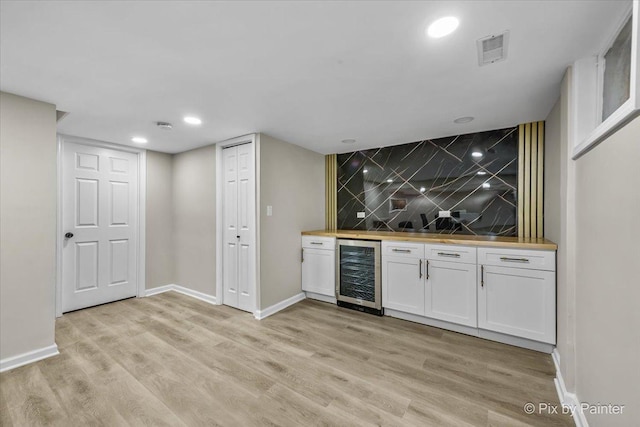 bar featuring wine cooler, wooden counters, light wood-type flooring, and white cabinets