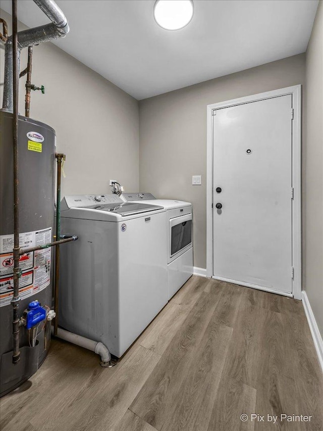 laundry area featuring water heater, washing machine and dryer, and light hardwood / wood-style flooring