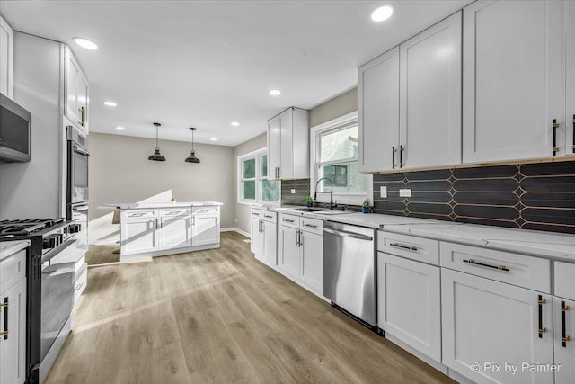 kitchen featuring appliances with stainless steel finishes, sink, white cabinets, backsplash, and light stone counters