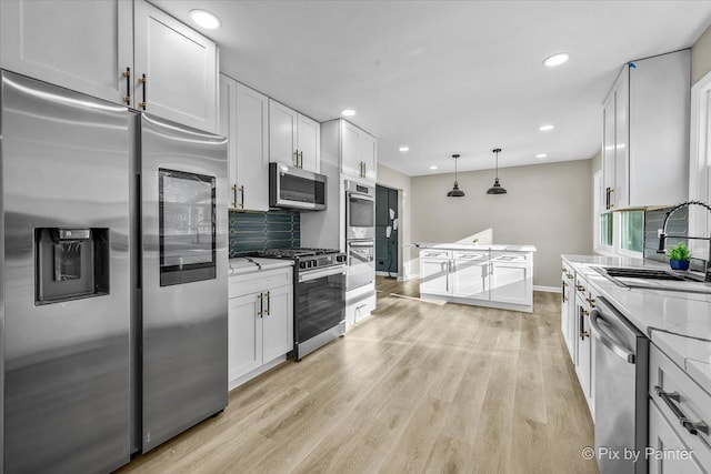 kitchen with stainless steel appliances, sink, white cabinets, and decorative backsplash