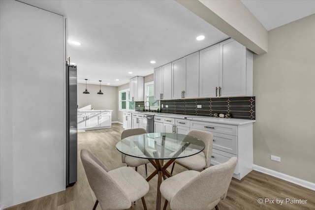 kitchen featuring sink, decorative light fixtures, white cabinets, stainless steel appliances, and backsplash