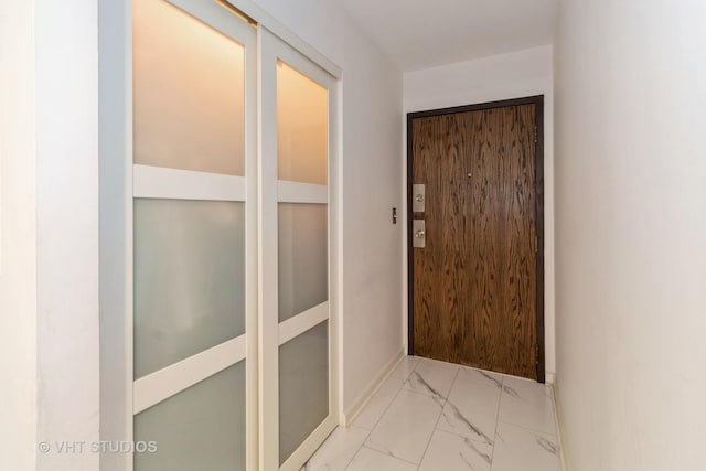 doorway featuring marble finish floor and baseboards