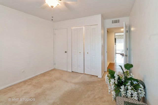 unfurnished bedroom with light carpet, visible vents, baseboards, a ceiling fan, and a closet