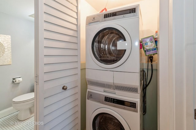 laundry room featuring tile patterned floors, stacked washer and clothes dryer, baseboards, and laundry area