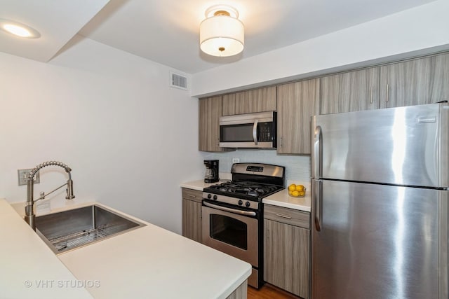 kitchen with a sink, visible vents, light countertops, appliances with stainless steel finishes, and tasteful backsplash