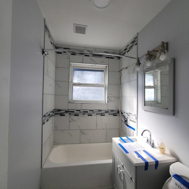 full bathroom with vanity, tiled shower / bath combo, and toilet