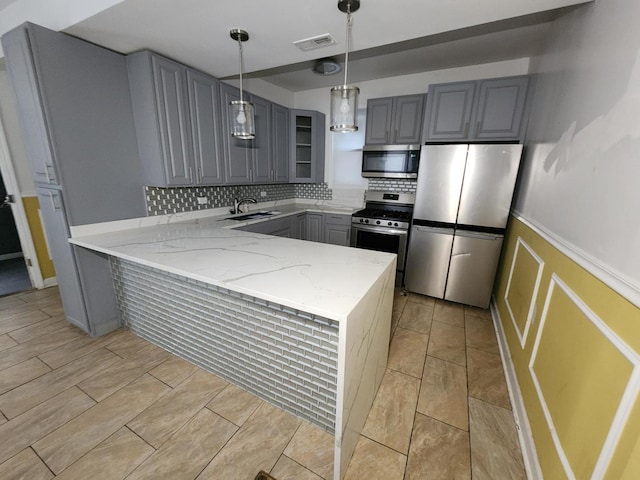 kitchen featuring sink, gray cabinets, appliances with stainless steel finishes, light stone counters, and kitchen peninsula