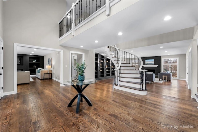 foyer entrance featuring a large fireplace, hardwood / wood-style floors, and a high ceiling