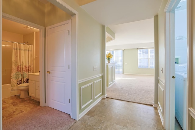 corridor featuring washer / clothes dryer and light carpet