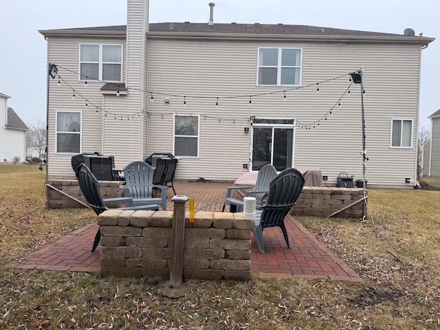 back of house featuring a patio, a yard, and an outdoor fire pit