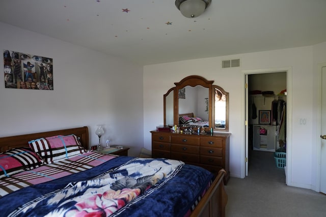 carpeted bedroom featuring a walk in closet