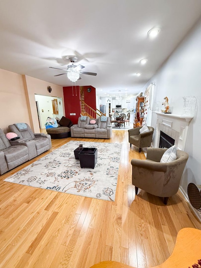 living room featuring hardwood / wood-style flooring, ceiling fan, and a fireplace