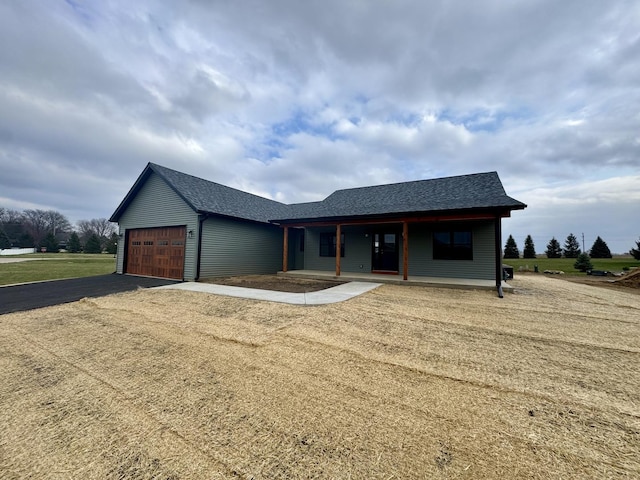 view of front of property featuring a porch, a shingled roof, a garage, and aphalt driveway