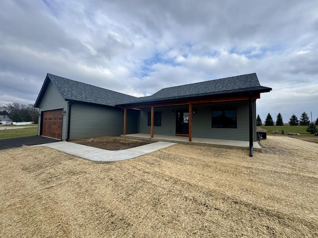 view of front of property with a porch, a shingled roof, a garage, and aphalt driveway