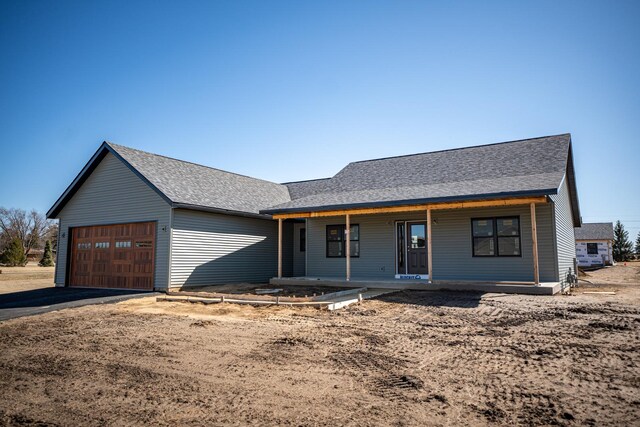 view of front of property with roof with shingles, aphalt driveway, a porch, and an attached garage