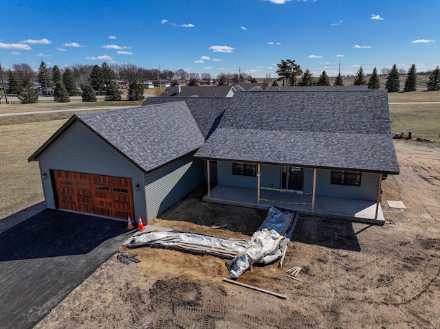 ranch-style home featuring aphalt driveway, roof with shingles, and an attached garage