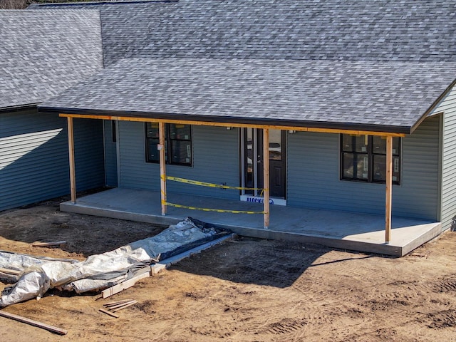 view of front facade featuring a patio area and roof with shingles